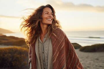 Poster - Portrait of a cheerful woman in her 40s dressed in a warm wool sweater isolated in beautiful beach sunset