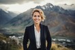 © Markus Schröder - Portrait of a cheerful woman in her 40s dressed in a stylish blazer in backdrop of mountain peaks