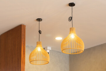 Wall Mural - Two wooden lamps hanging from the ceiling, one is lit up