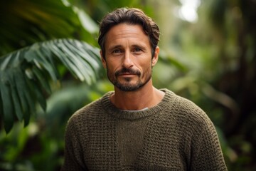 Poster - Portrait of a tender man in his 40s wearing a cozy sweater in front of lush tropical rainforest