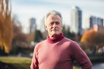 Wall Mural - Portrait of a tender man in his 70s showing off a thermal merino wool top isolated on vibrant city park