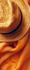 Wall Mural - A straw hat is on top of a piece of orange fabric