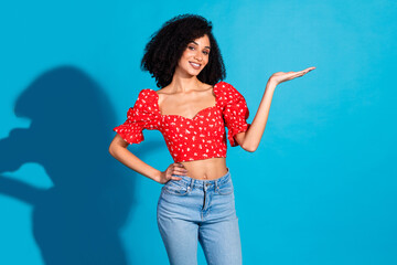 Portrait of gorgeous young woman hold empty space ad wear top isolated on blue color background