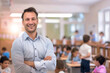 © tiena - Smiling male teacher against the backdrop of a blurred classroom