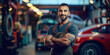 © PRASANNAPIX - male mechanic standing with his arms crossed, smiling wearing grey overalls and a black shirt