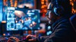 © imagemir - A gamer plays video games on his computer while wearing headphones in a dimly lit room