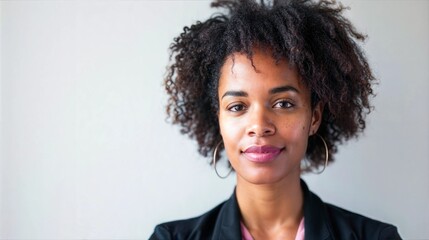 Wall Mural - A woman with curly dark brown hair smiles at the camera in front of a white wall