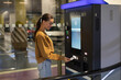 © Home-stock - Young woman driver paying for ticket in parking meter near terminal in the underground parking area