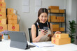 © amnaj - Asian sme business woman is working in her home office, using her smartphone to check a customer order on an online marketplace