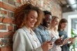 © Yuliia - Beautiful diverse businesspeople smiling and using smartphones near the brick wall in the office.