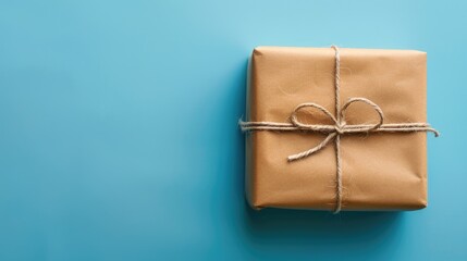 Sticker - Gift box wrapped in brown paper on a blue background Overhead view festive theme