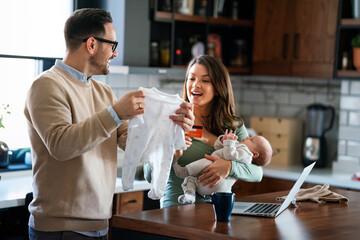 Wall Mural - Cheerful young family with a baby child enjoying online purchasing on the internet at home