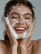 © vefimov - Happy smiling woman with suds on her face, indicating a facial or skin treatment.