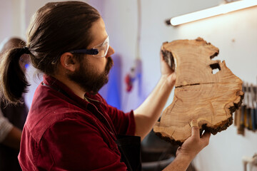 Sticker - Manufacturer respecting safety codes doing last touches on piece of wood before using it for furniture assembly. Woodworking specialist examining timber block for damages