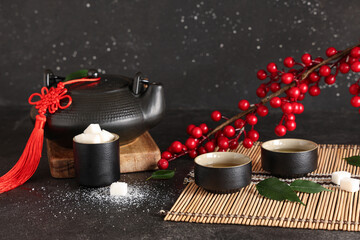 Wall Mural - Teapot with cups of tea, sugar and viburnum branch on black grunge background