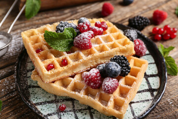 Wall Mural - Plate of sweet Belgian waffles with different fresh berries and mint on wooden background