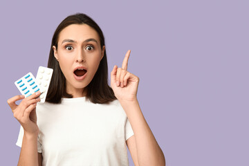 Sticker - Shocked young woman with pills pointing up on lilac background