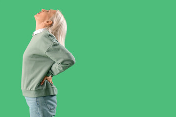 Poster - Mature woman suffering from back pain on green background