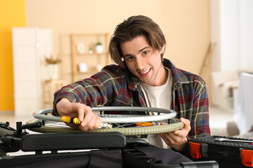 Wall Mural - Young man with pliers repairing wheelchair at home