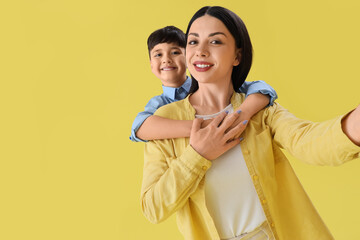 Poster - Little boy hugging his mother on yellow background