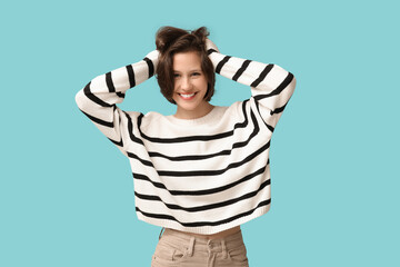 Poster - Happy young woman in stylish striped sweater on blue background