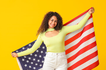 Wall Mural - Young African-American woman with USA flag on yellow background