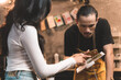 © Atthapon - woman customer in restaurant choosing food on menu in tablet and waiter take a note for the order form customer. woman in restaurant with the man owner on waiter uniform and service customer.