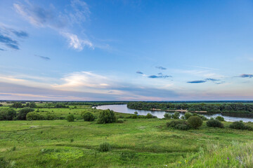 Wall Mural - a breathtaking view of a river winding through a landscape of rolling green meadows, with a tranquil