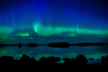 Wall Mural - northern lights dancing over calm lake in farnebofjarden national park in north of sweden.