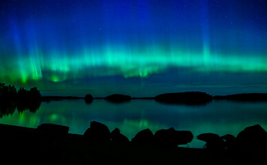 Wall Mural - northern lights dancing over calm lake in farnebofjarden national park in north of sweden.