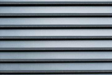 Close-up of a fragment of a fence made of gray horizontal metal panels imitating boards. Background. Texture.