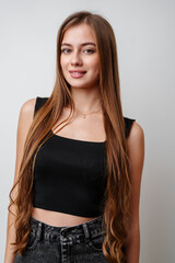 Wall Mural - Young Woman With Long Brown Hair Wearing Black Crop Top and Jeans