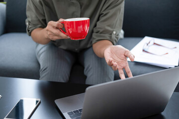 Wall Mural - Businesswoman sitting at desk on couch in workplace or at home working on laptop and analyzing data on charts and graphs and writing on papers to make business plan and strategies for company, 