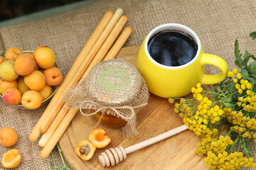 Summer still life picture with coffee, honey, apricots and yellow flowers 