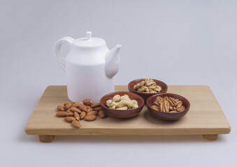 Sticker - Close-up of dried nuts like walnut, pecan, cashew nuts on a dish with almond and a white kettle on wood cutting board, South Korea
