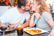 © simona - Romantic date at the restaurant with young mature couple kissing before eat food. Love and relationship celebrating anniversary together having lunch outdoor. Tourists enjoy outdoor leisure activity