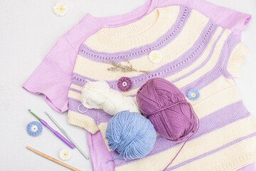 Wall Mural - Handmade crocheted baby t-shirt in lilac tones. Stuff contains thread, hooks, knitting needles