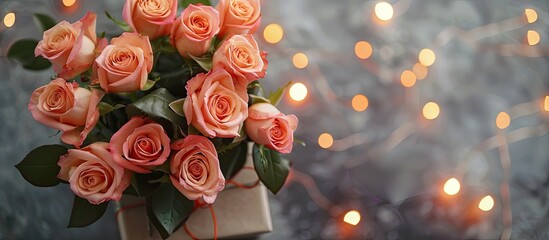 Leinwandbilder - Top view of a bouquet of fresh roses in a gift box on a gray table creating a flat lay composition with bokeh lights in the background creating a copy space image
