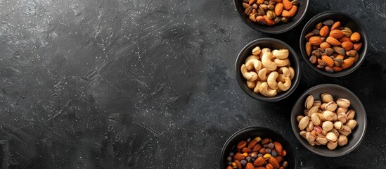Aufkleber - A black table displaying four bowls filled with various nuts like cashews almonds walnuts and pistachios offering a top view with a blank area for additional content a copy space image