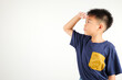 © sorapop - Searching concept. Asian young boy kid looking far away with hand over head at studio shot isolated on white background, Portrait of Happy primary child looking at distance with eyes shaded