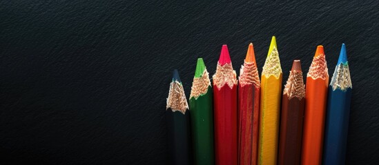 Aufkleber - Colorful pencils displayed against a black backdrop with copy space image