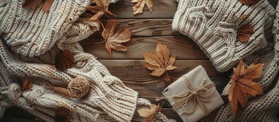 Wall Mural - Top view of a cozy autumn flat lay with warm sweaters craft gift and dried leaves capturing the essence of slow living in the fall season with a copy space image