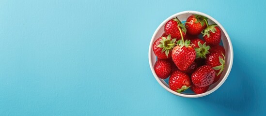 Poster - Delicious berry dessert featuring fresh ripe strawberries in a cup on a blue paper background viewed from the top with copy space image