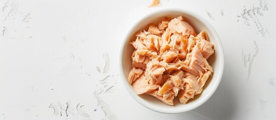 Poster - Top view of canned tuna in a white bowl on a white background with soft lighting in a studio shot allowing for copy space in the image