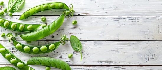 Wall Mural - Top down view of fresh green pea pods on a white wooden table with space for text or image insertion. Creative banner. Copyspace image