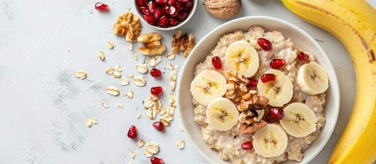 Aufkleber - Flat lay composition of a nutritious breakfast featuring oatmeal topped with nuts pomegranate seeds and bananas on a white surface with room for text or other images copy space image