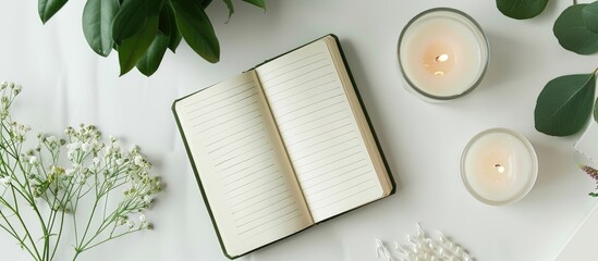 Aufkleber - From a top down view a flat lay arrangement showcasing a blank notebook a flower and candles on a white surface provides a visually appealing copy space image