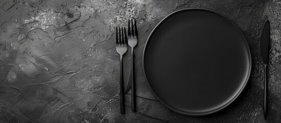 Aufkleber - Top view of a black plate and cutlery on a stone table set up with empty space for text or other elements in a flat lay composition. Creative banner. Copyspace image