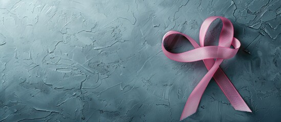 Poster - Breast cancer awareness concept displayed in a top view copy space image of a pink ribbon on a grey background