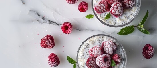 Poster - An aerial view of a breakfast presentation featuring chia pudding with frozen raspberries and cottage cheese in two small clear glasses with a copy space image